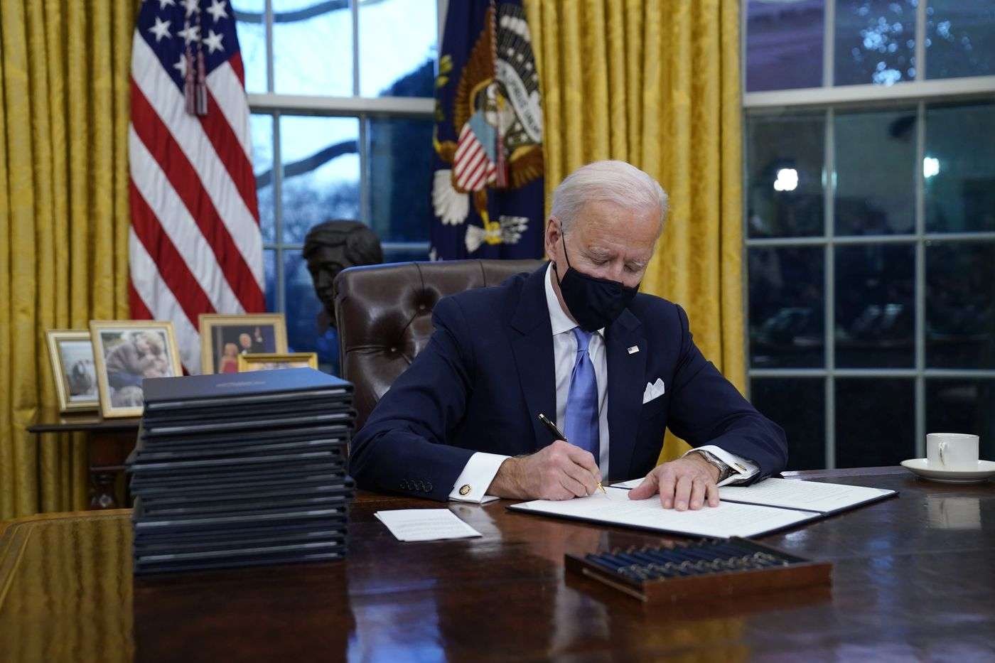 President Joe Biden signs his first executive order in the Oval Office of the White House on Wednesday.